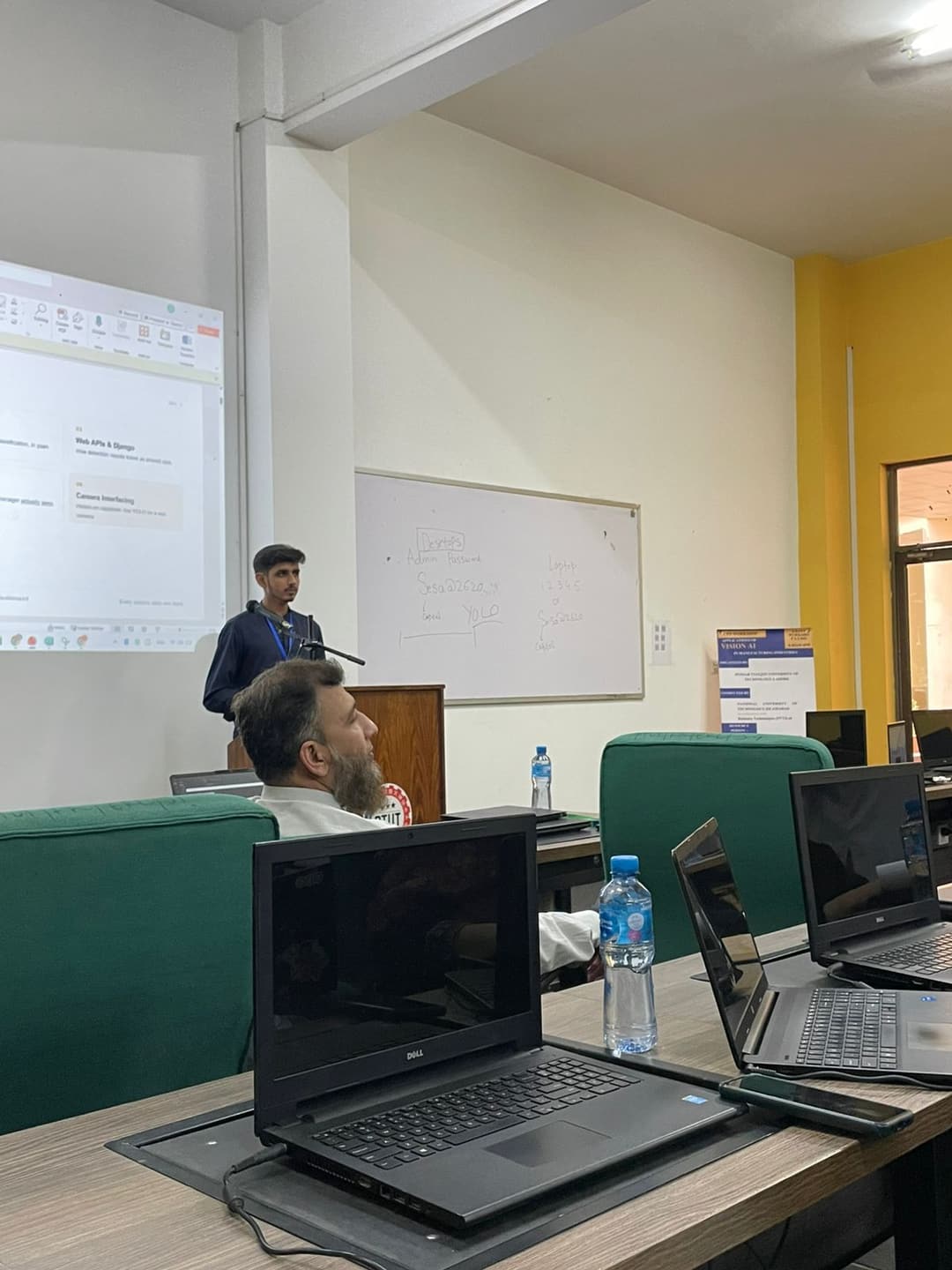 Hamza presenting from the lectern to attendees at rows of workstations in the PTUT computer lab.